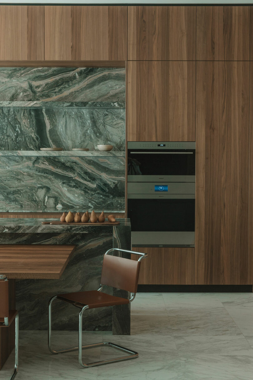 A modern kitchen with wood-paneled cabinets and a prominent green marble backsplash.