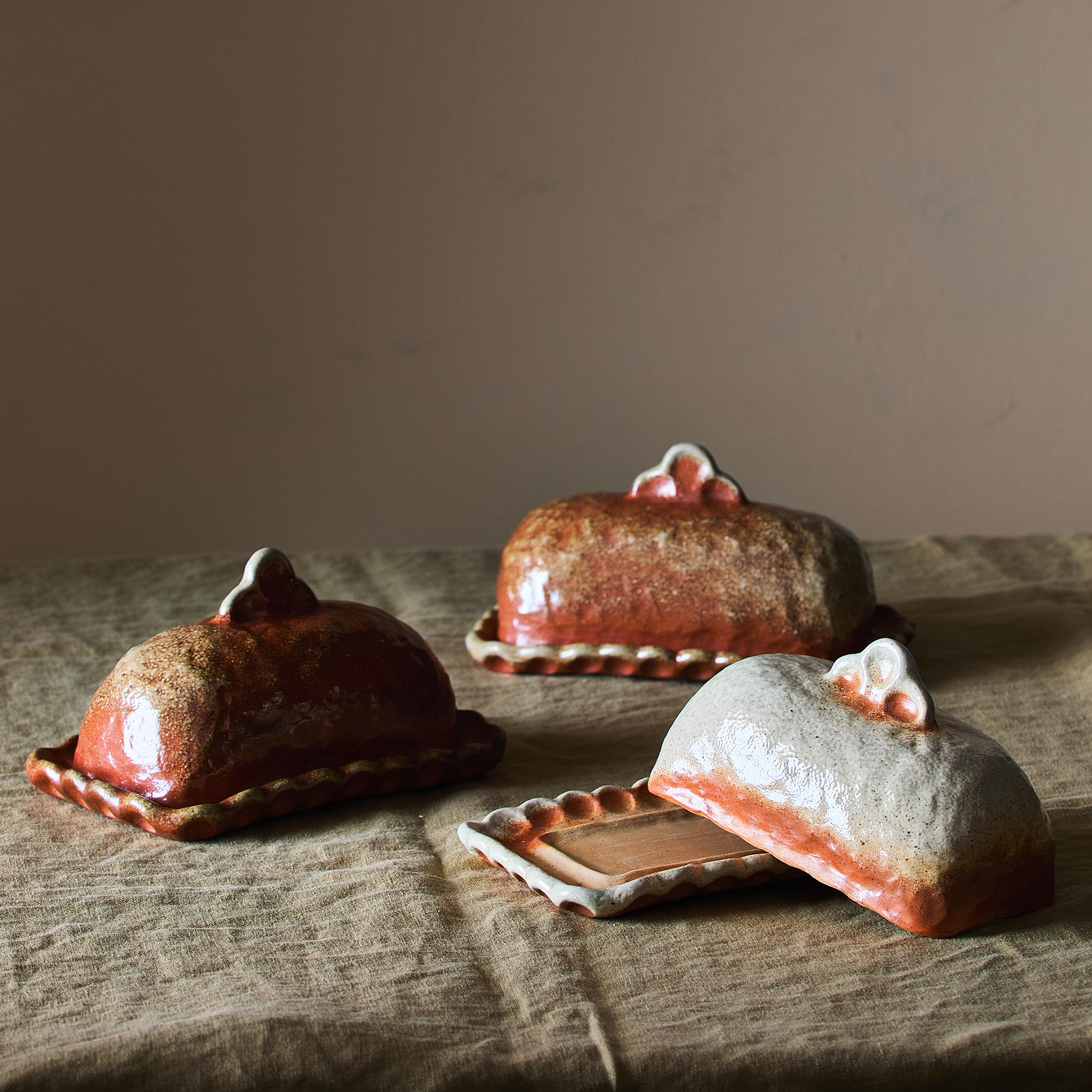 A minimalist, unglazed wood-fired ceramic butter dish showing rich, stone-like surface variations.