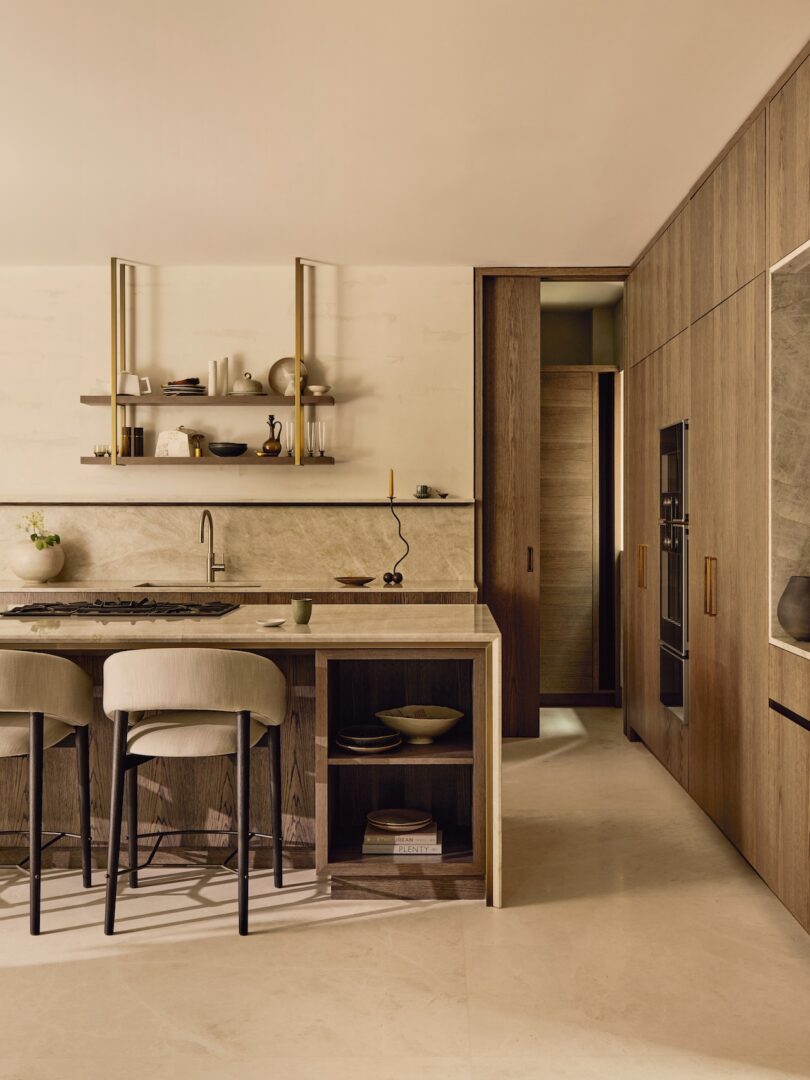 Modern kitchen featuring wood cabinetry, thick marble countertops, and artisanal pottery on open shelves.