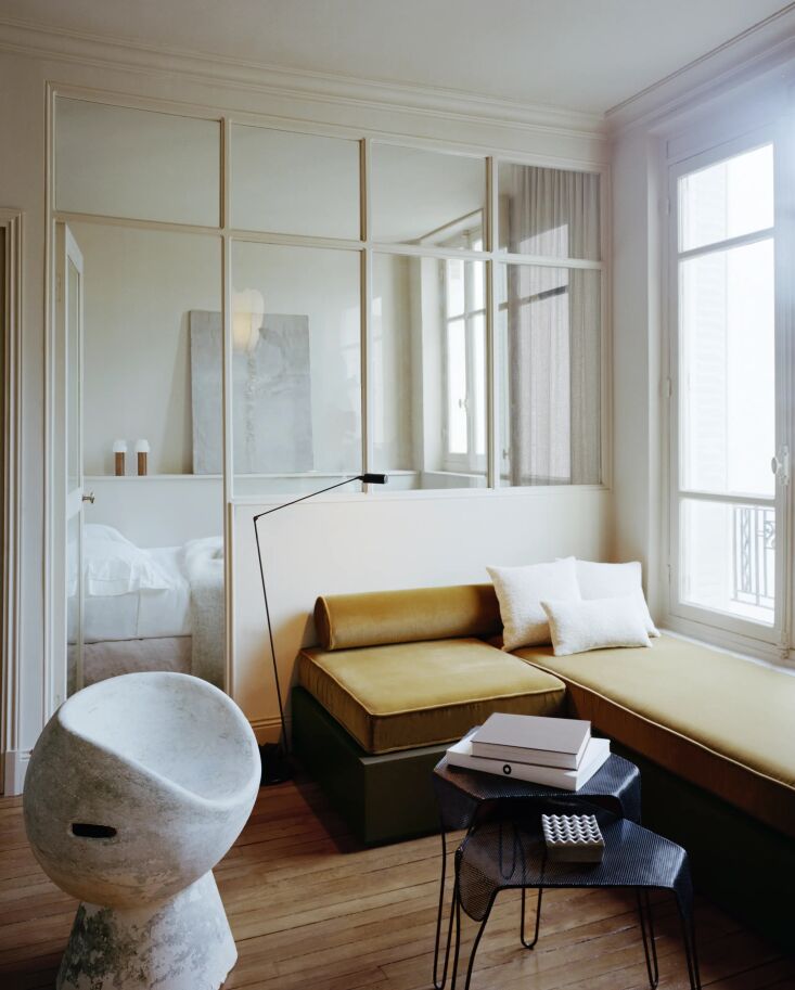 A living area featuring a custom bench, designer floor lamp, and vintage side chairs.