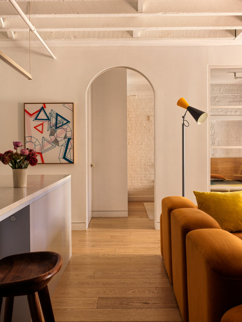 A living space featuring an original brick archway and dark timber ceiling beams.