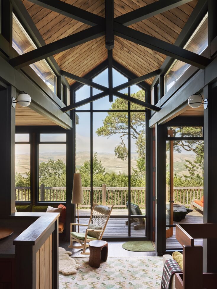 A Hans Wegner rocking chair and JB Blunk wooden stools on a patterned rug.