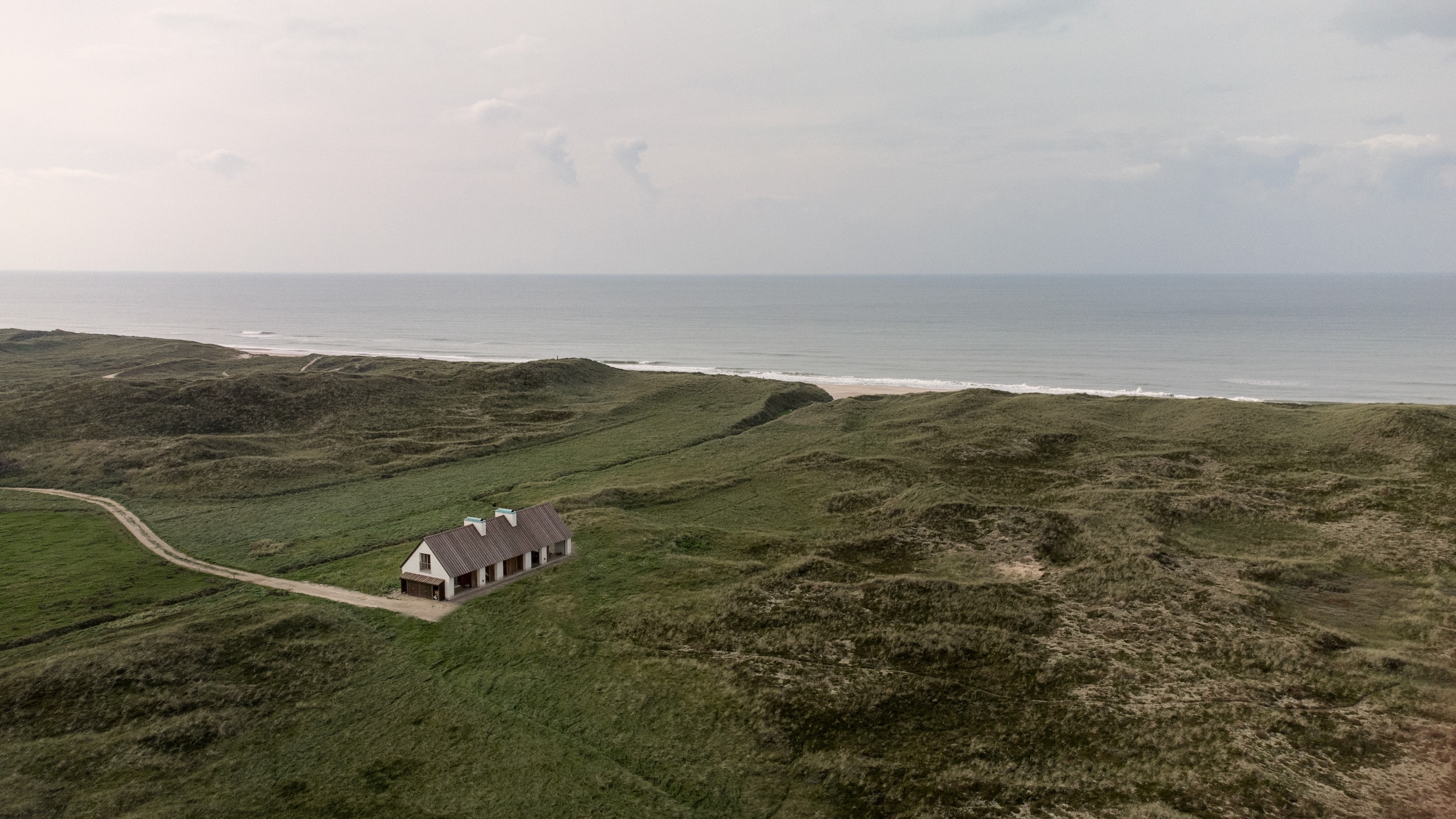 Exterior view of the Vipp Cold Hawaii house showing the west gable and surrounding untamed grassland.