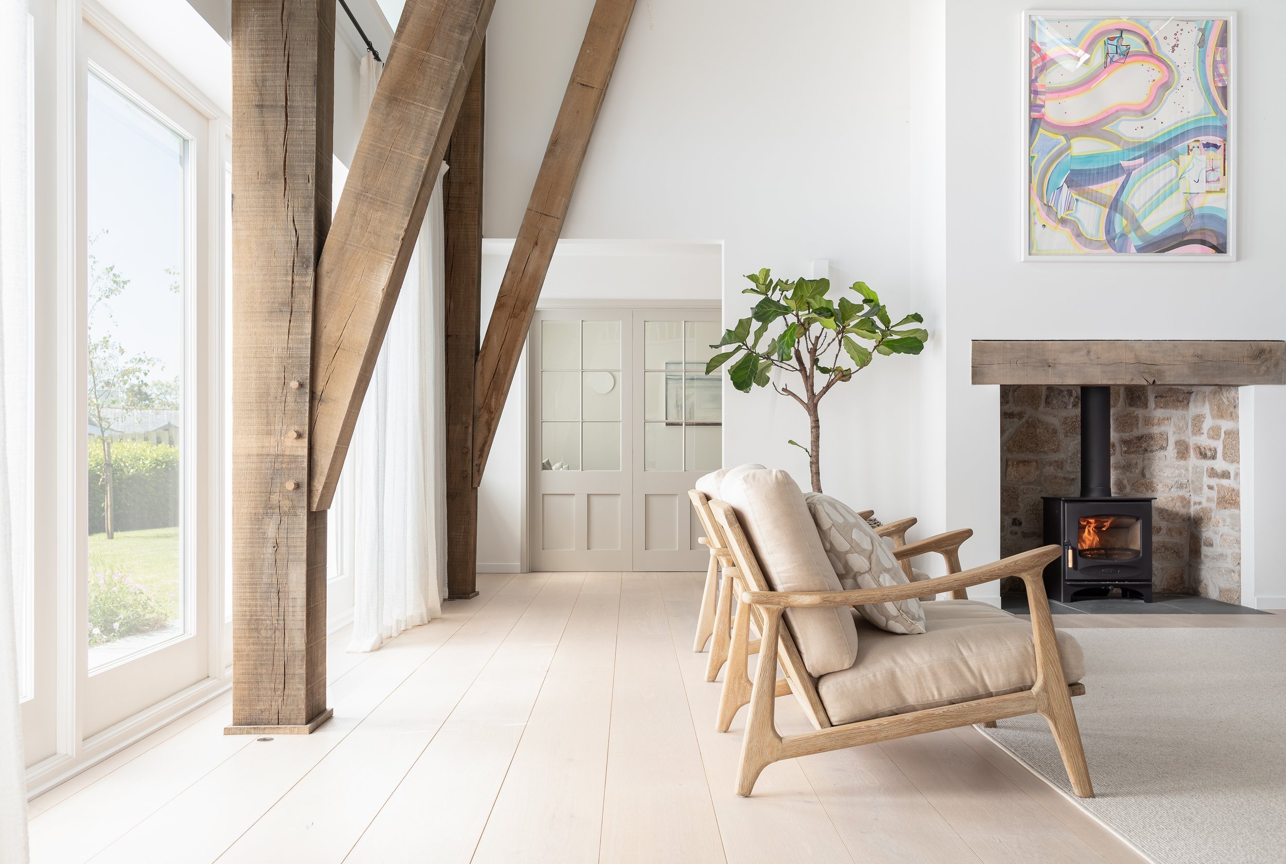 Vaulted ceiling of a modern barn showing exposed straight oak beams in a contemporary cruck frame style.