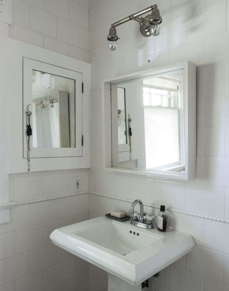 A bathroom vanity mirror flanked by light fixtures using small chrome-tipped bulbs.