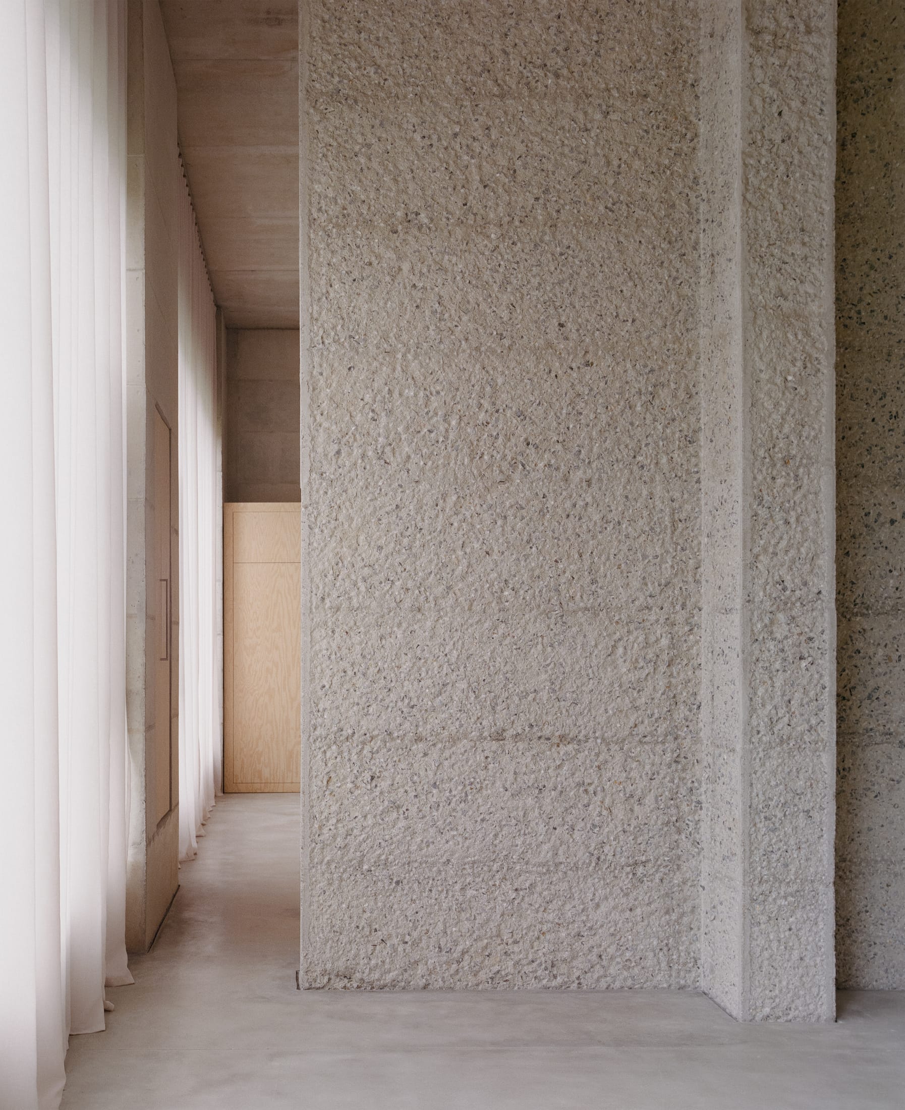 A minimalist room with soft light reflecting off concrete walls and no visible ceiling fixtures.