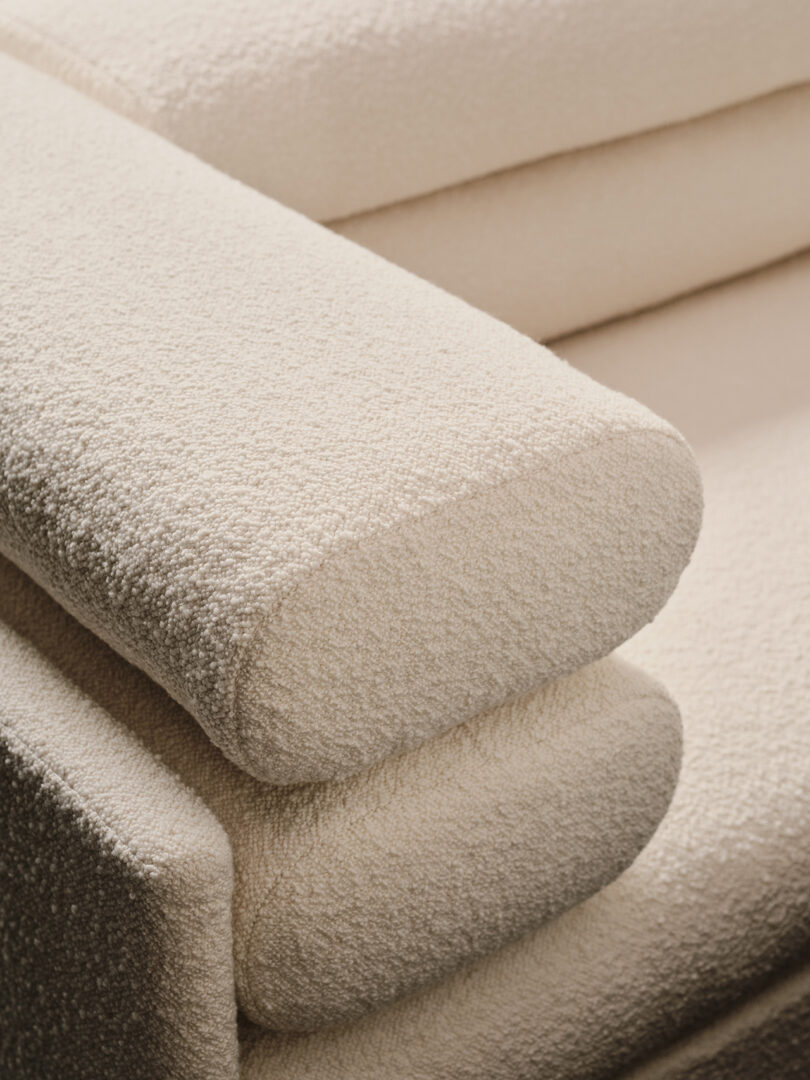 Close-up of the textured beige fabric and overlapping cushion details of the Elogio sofa.