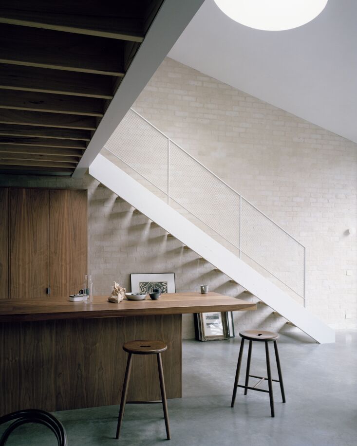 A modern kitchen with American walnut cabinetry and polished concrete floors.