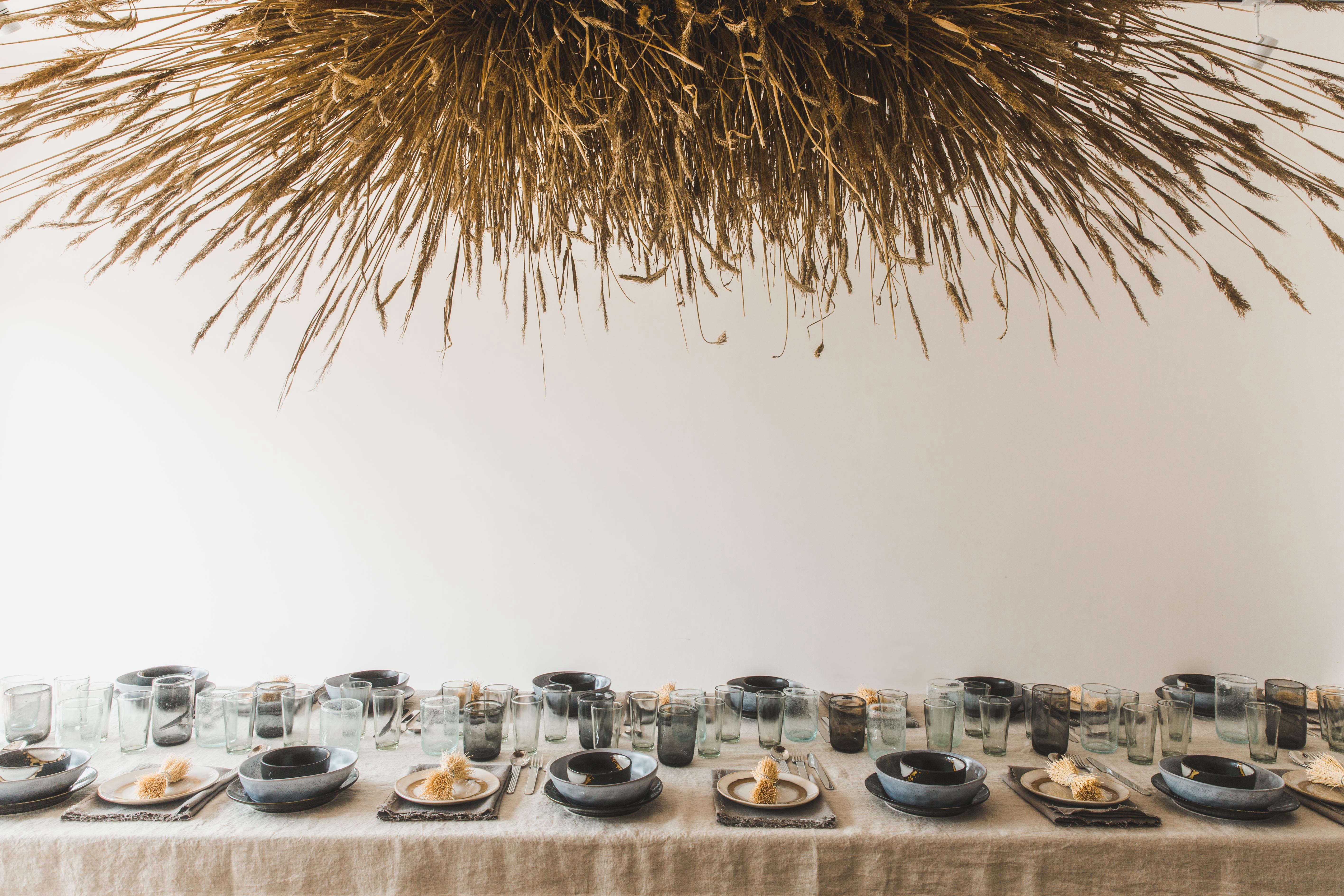 Full view of a rustic dining table set with neutral linens and sculptural dried botanicals.