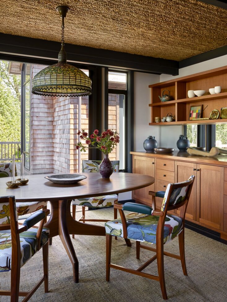 A dining room with a custom woven rush ceiling and Josef Frank upholstered chairs.