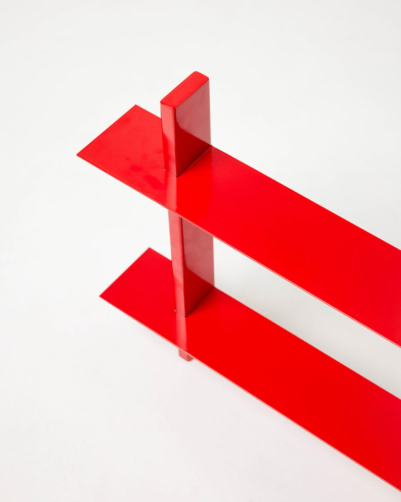 Two glossy red rectangular metal shelves intersecting perpendicularly.