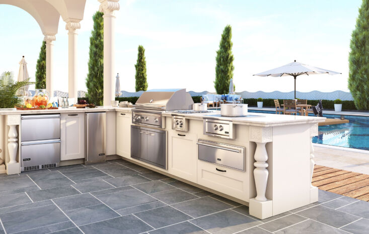 A sleek outdoor kitchen area located next to a swimming pool with lounge seating.