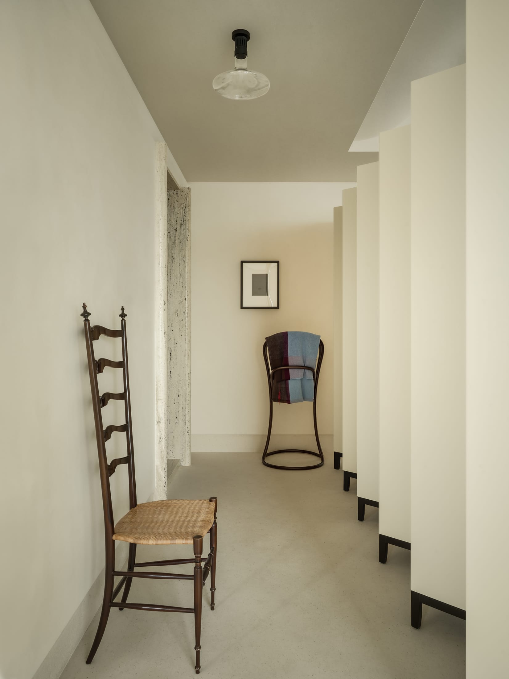 A sleek, minimalist white spiral staircase ascending through a sunlit architectural void.