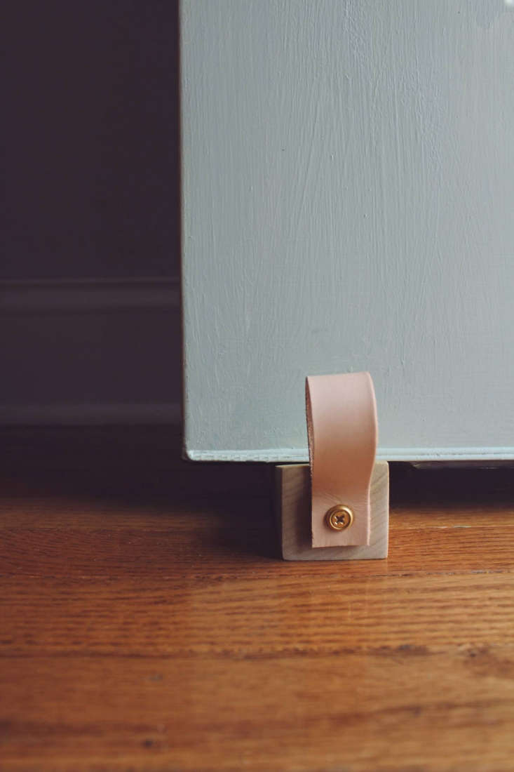 The finished wooden doorstop in use at the base of a modern interior door.