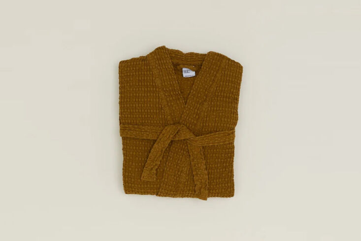 A crisp white cotton waffle-weave bathrobe hanging on a hook.