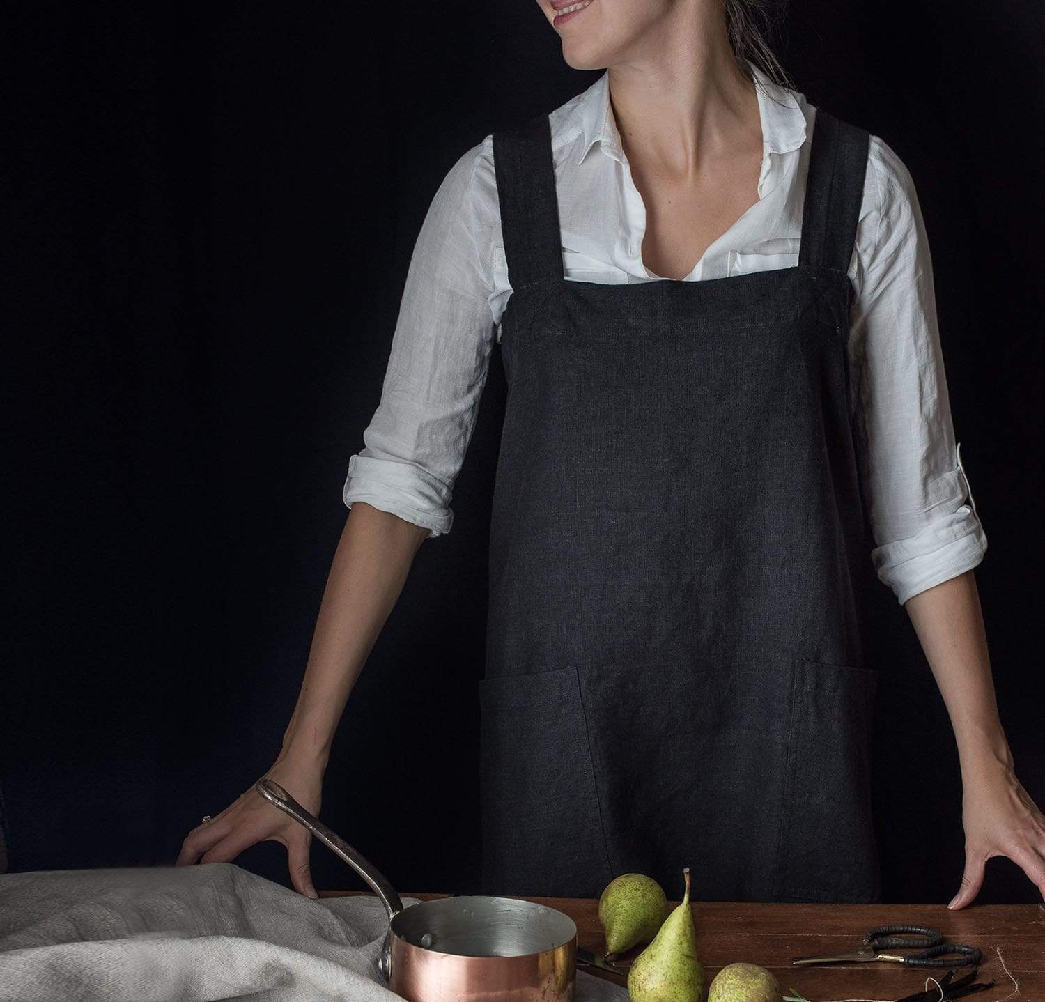 A simple, light-colored linen pinafore apron with large side pockets.