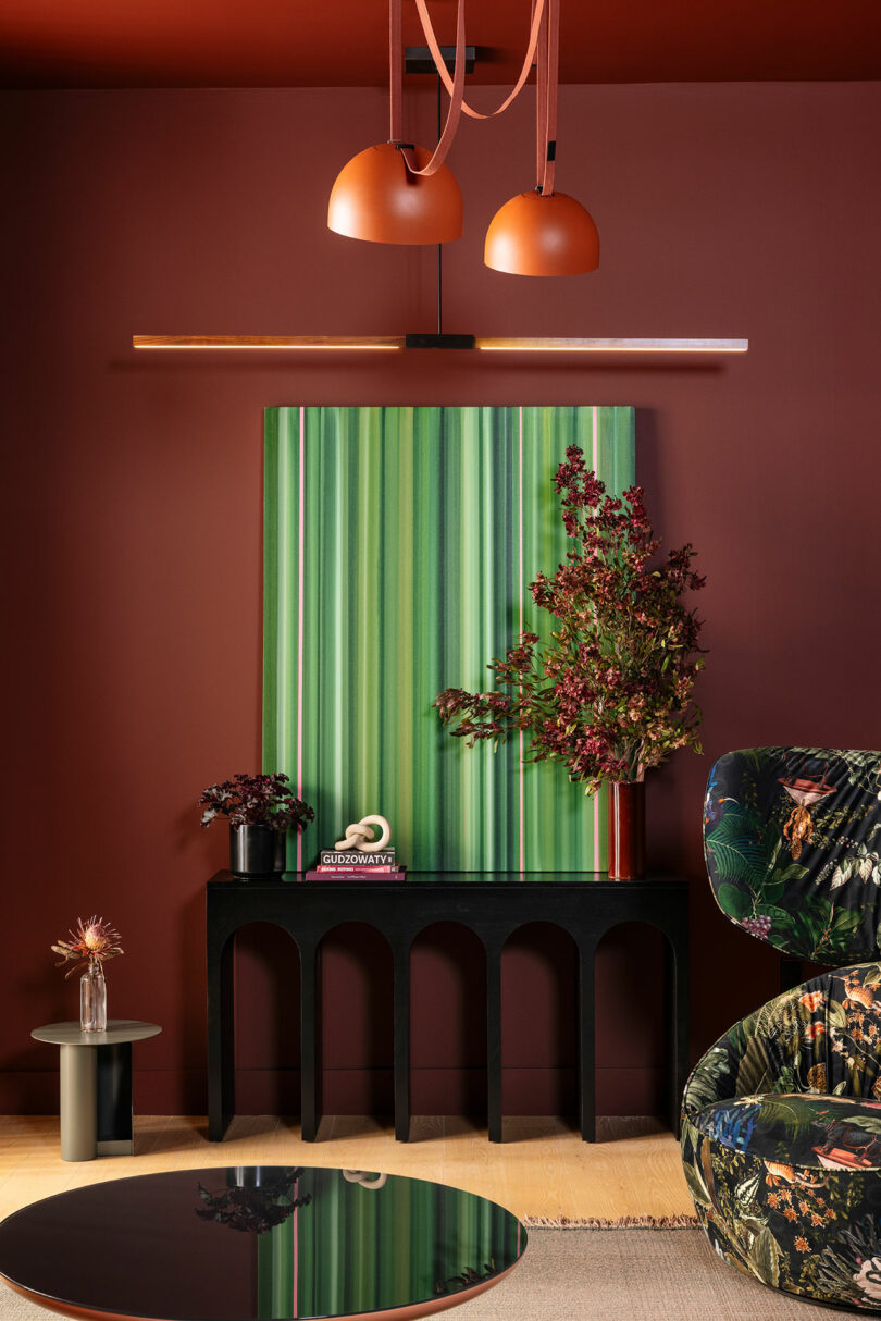 A curated living room vignette with reddish-brown walls, striped artwork, and diverse lighting fixtures.