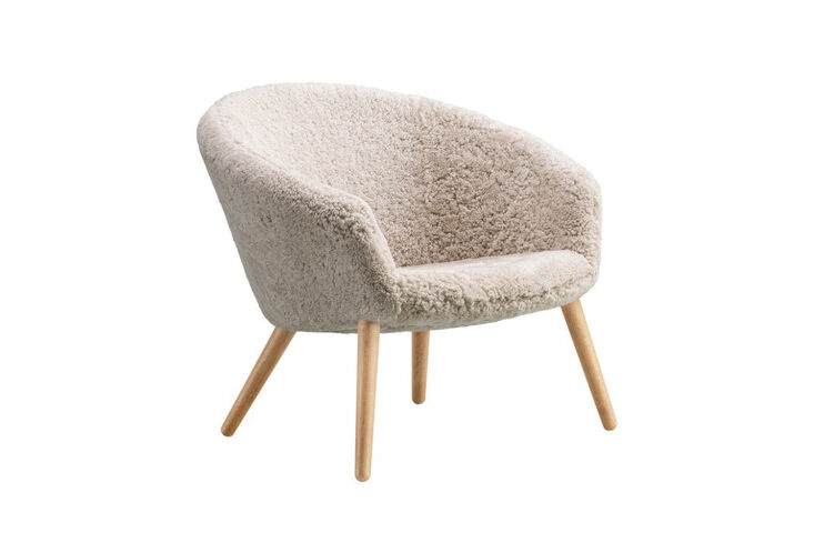 Ditzel Lounge Chair by Fredericia in sheepskin with four simple wooden legs and a wide curved back.