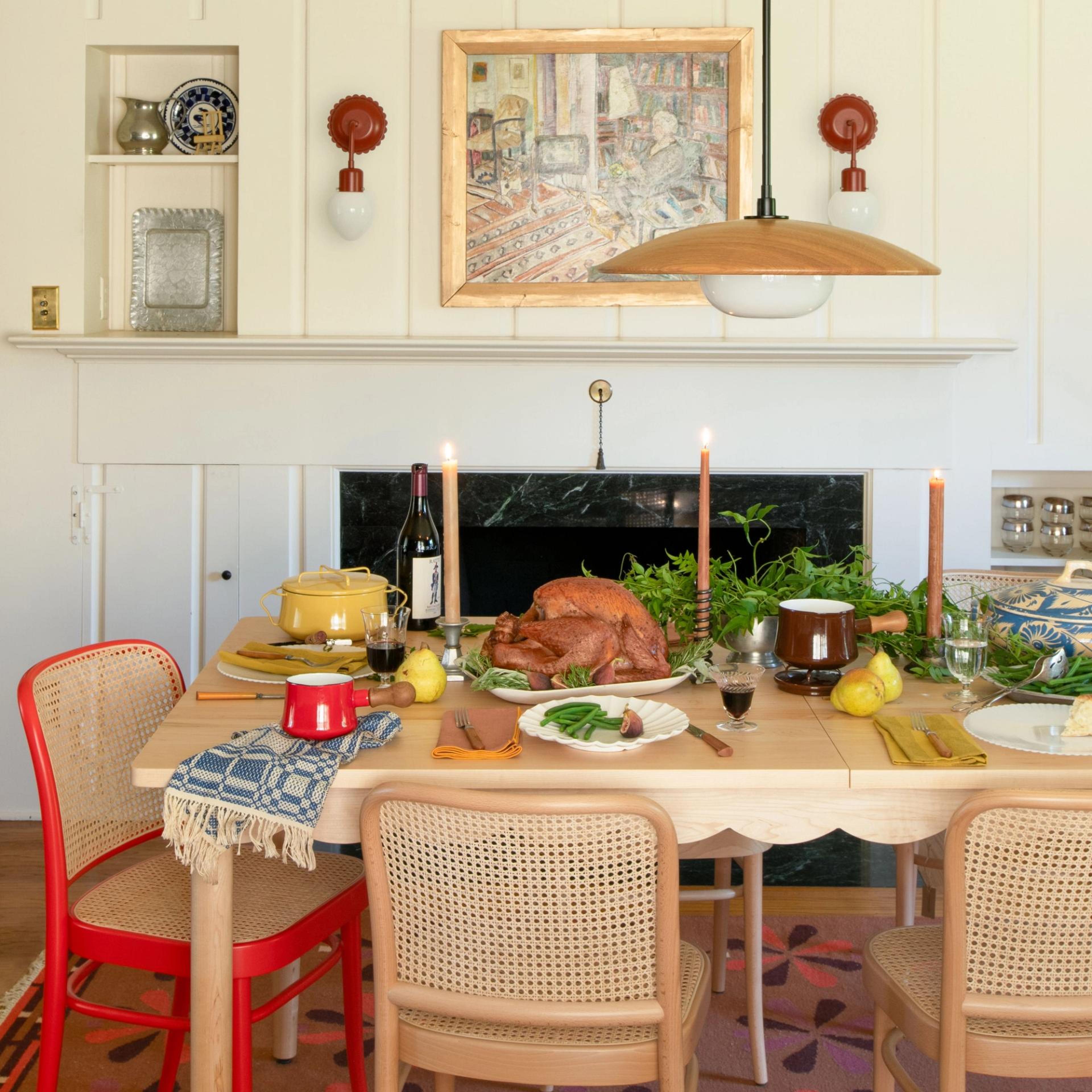 A dinner table scene with candles, food, and mixed tableware under warm lighting.