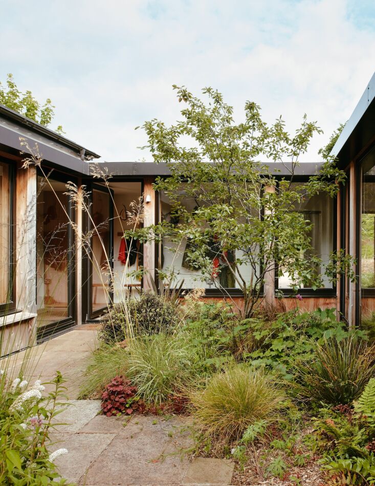 View of a central interior courtyard through large glass doors from the house interior.