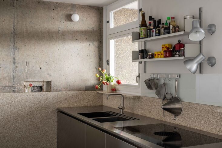 A kitchen featuring a stainless steel and concrete palette with a bespoke terrazzo floor.