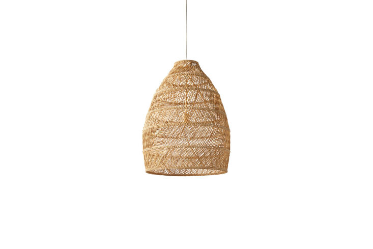 A woven bell-shaped pendant light hanging inside a canvas tent.