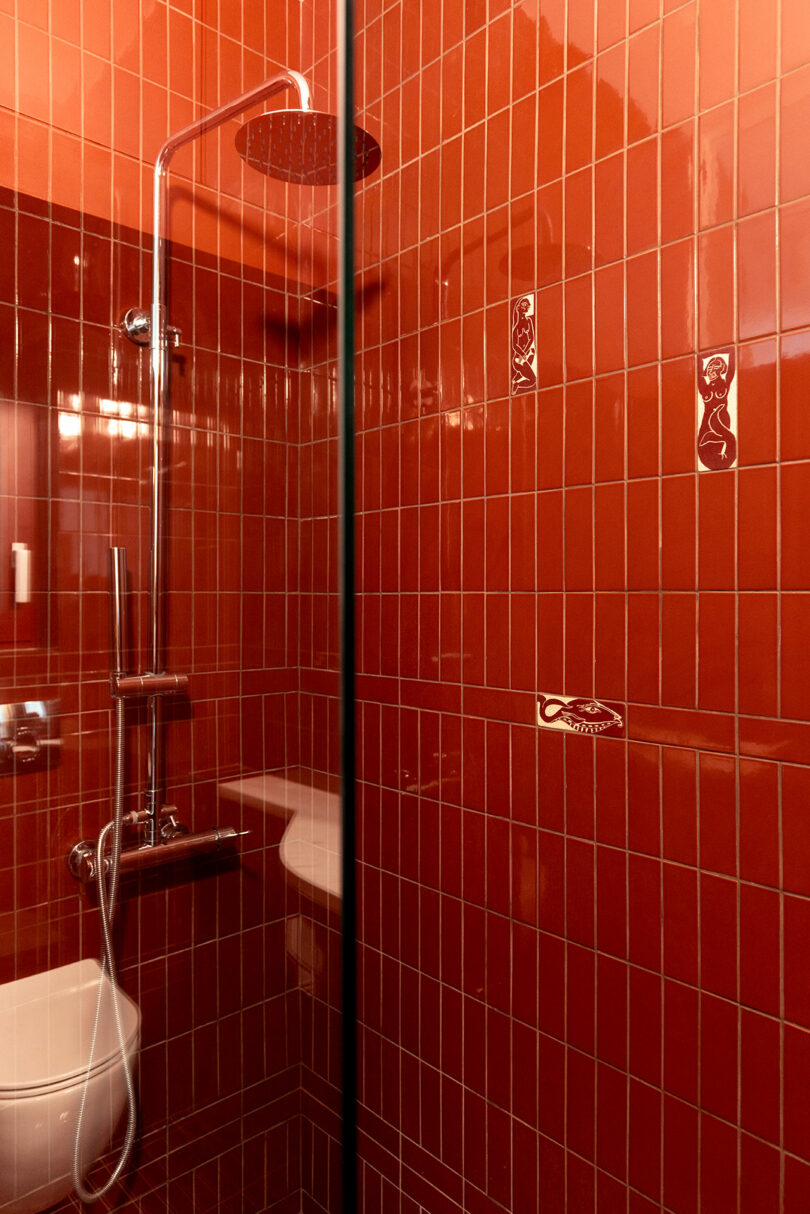 A vibrant bathroom interior with glossy red-tiled walls and a modern rainfall showerhead.
