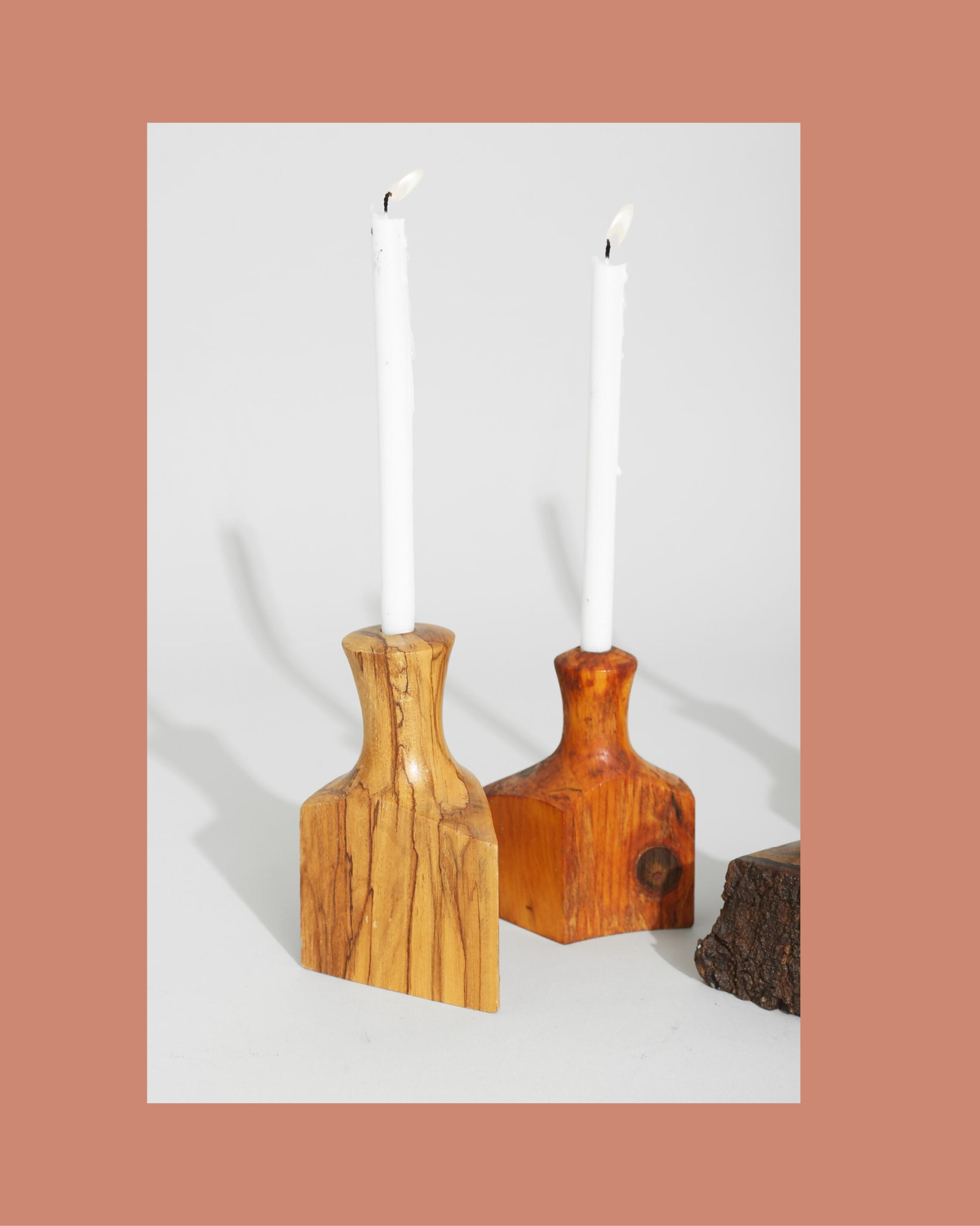 A set of organic, slightly irregular hand-carved wooden candleholders on a dining table.