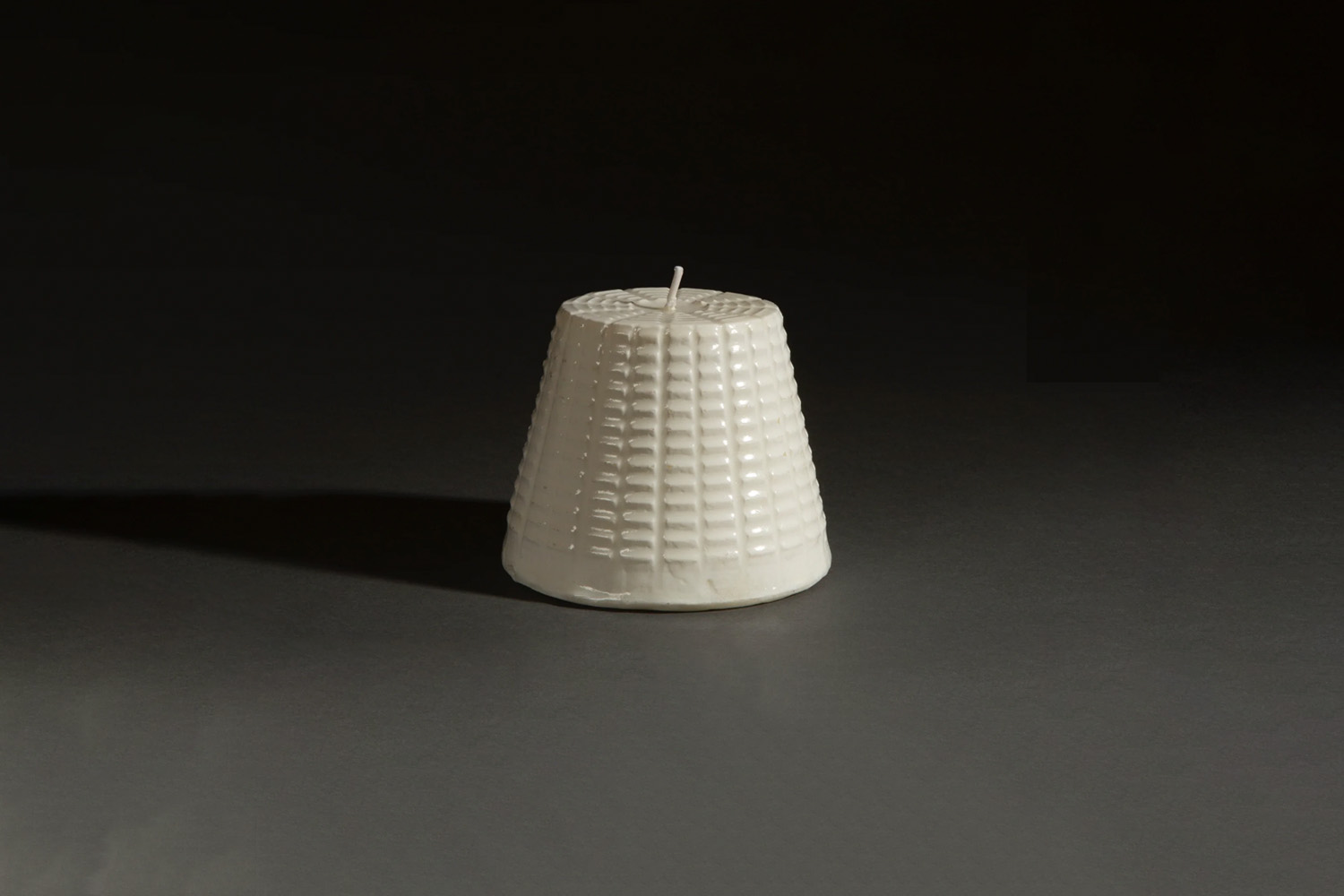 A candle shaped like a piece of ricotta cheese sitting on a decorated plate.