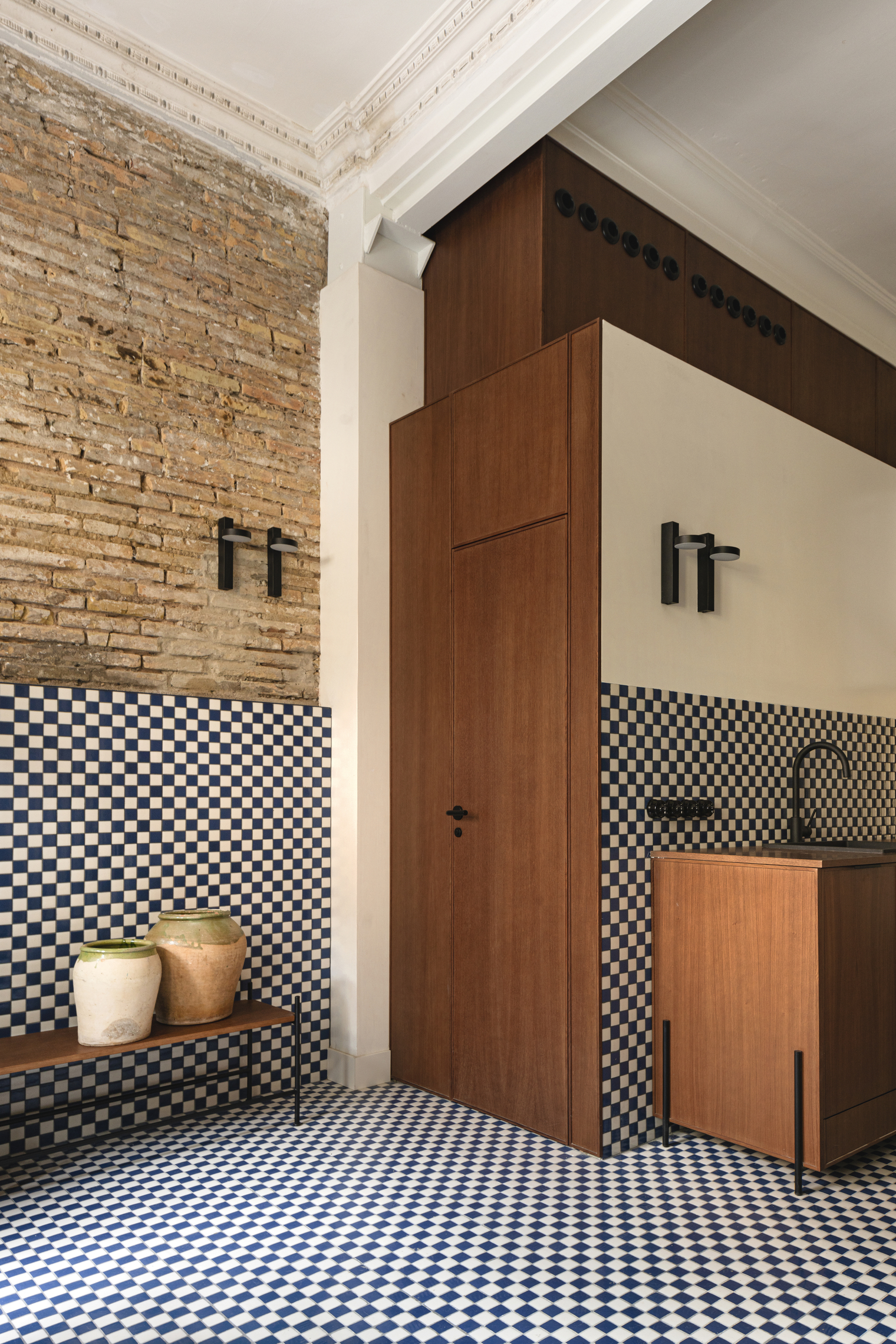 High-angle shot showing the continuity of blue-and-white checkered tiles from the floor up onto the lower walls.