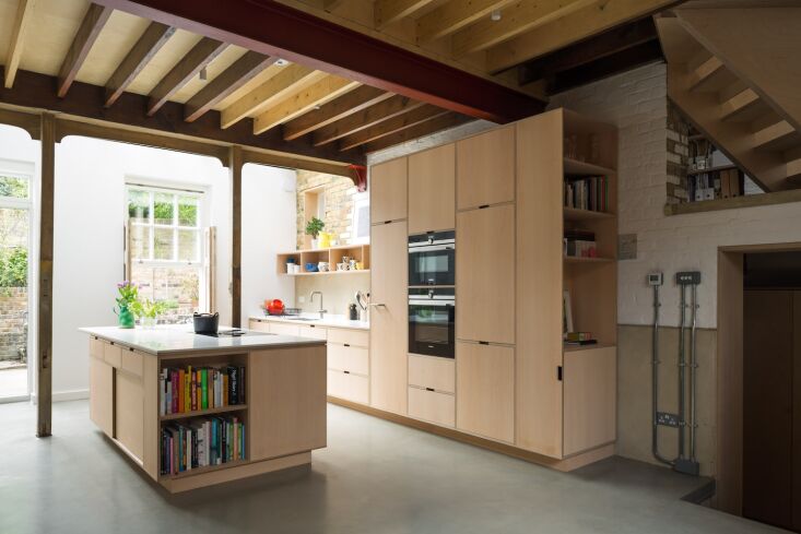A kitchen island with a built-in bookshelf at the end, filled with cookbooks.