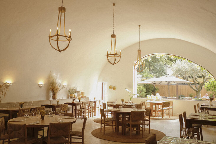 The restaurant area of Le Moulin featuring a dramatic stone arched ceiling and woven rugs.