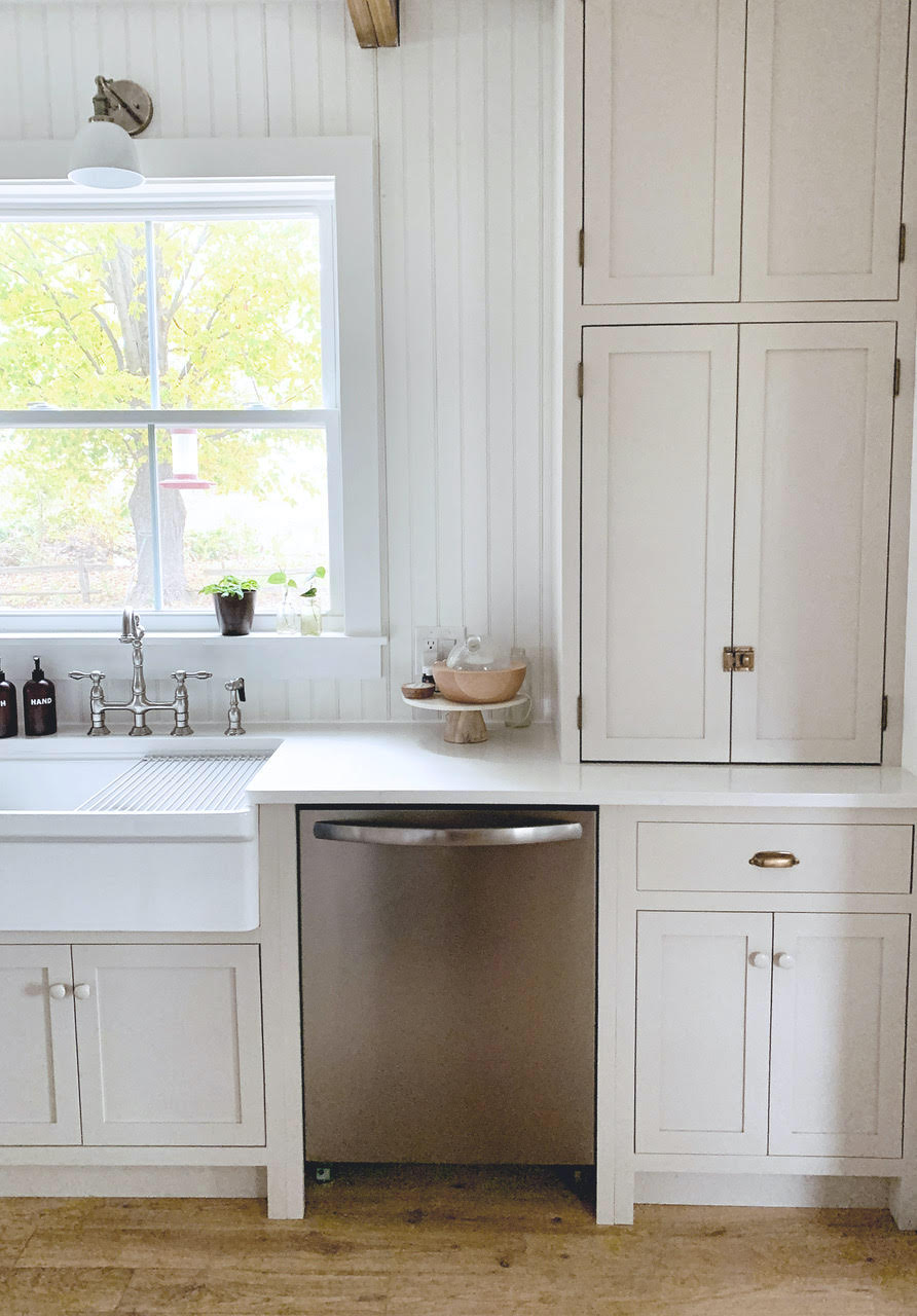 A stainless steel dishwasher installed between white kitchen cabinets, showing a lack of visual continuity.