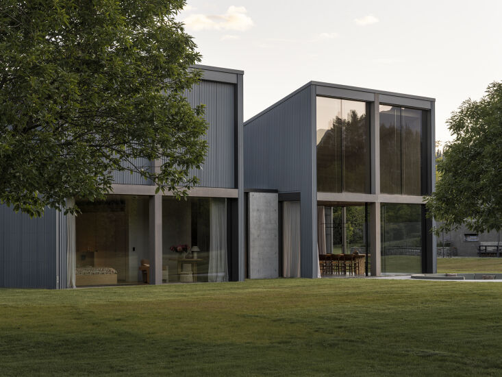 A wide architectural shot of the modular volumes of Orchard House against the New Zealand hills.