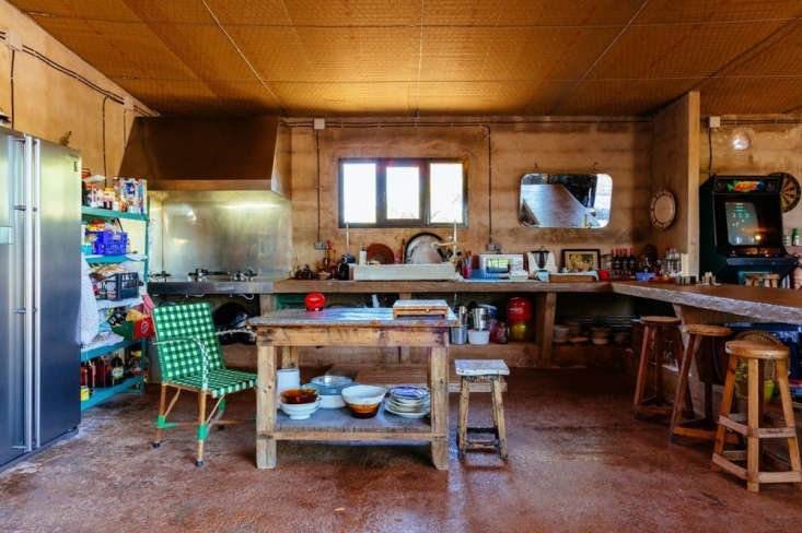 A rustic kitchen in a former garden potting shed with a cement floor and vintage plant table.