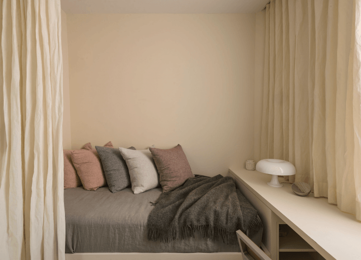 A trundle daybed painted in light beige styled in a serene bedroom setting designed by Studio Oink.