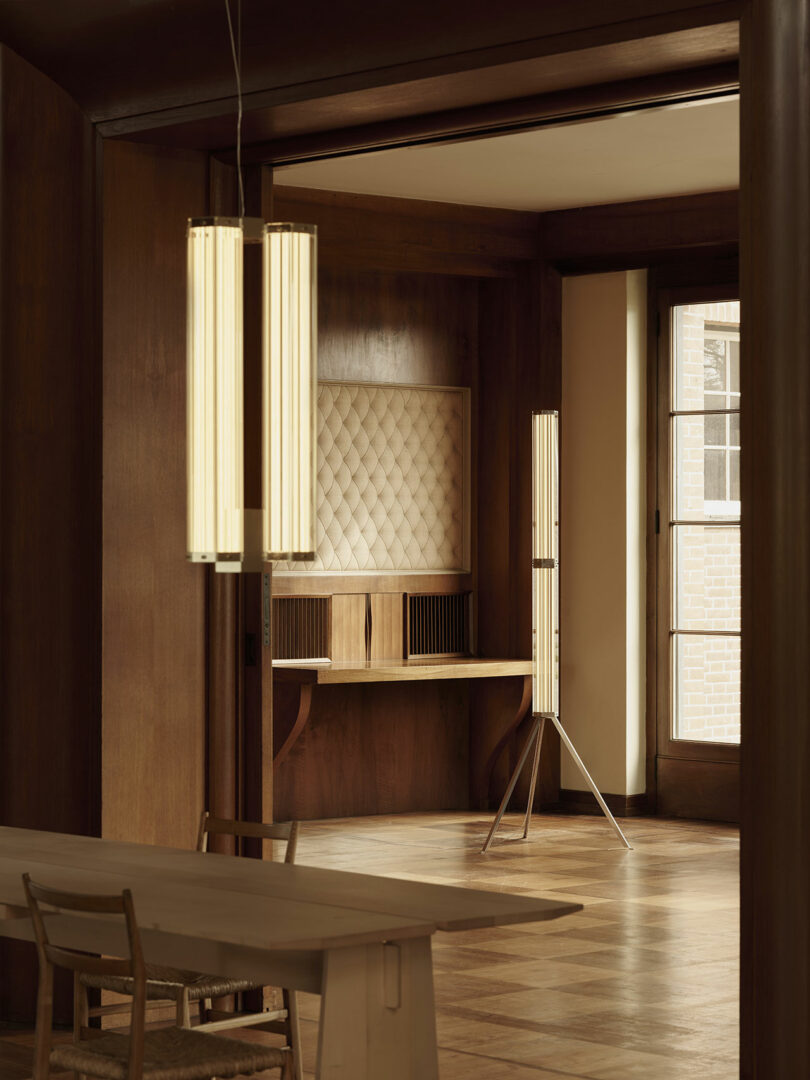 A minimalist room with wood-paneled walls, a built-in desk, and modern vertical light fixtures.
