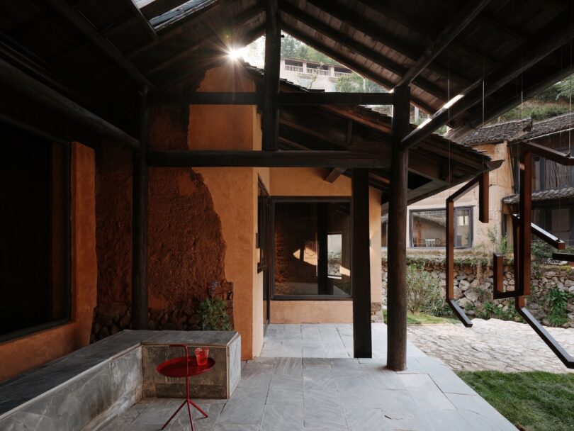 Rustic courtyard with textured mud walls, slate floors, and traditional wooden beams.