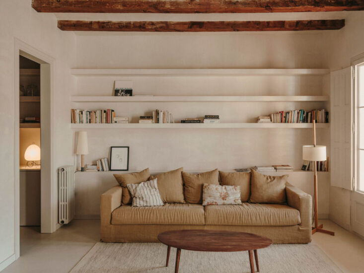 Básica lamp integrated into built-in wooden bookshelves in a Barcelona apartment.