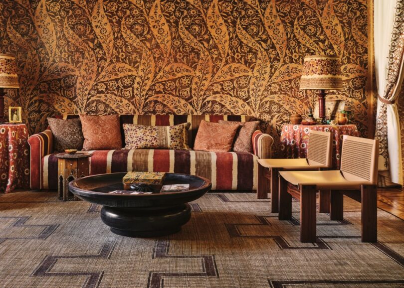 Two Monk armchairs styled in a maximalist living room with patterned wallpaper and a striped sofa.