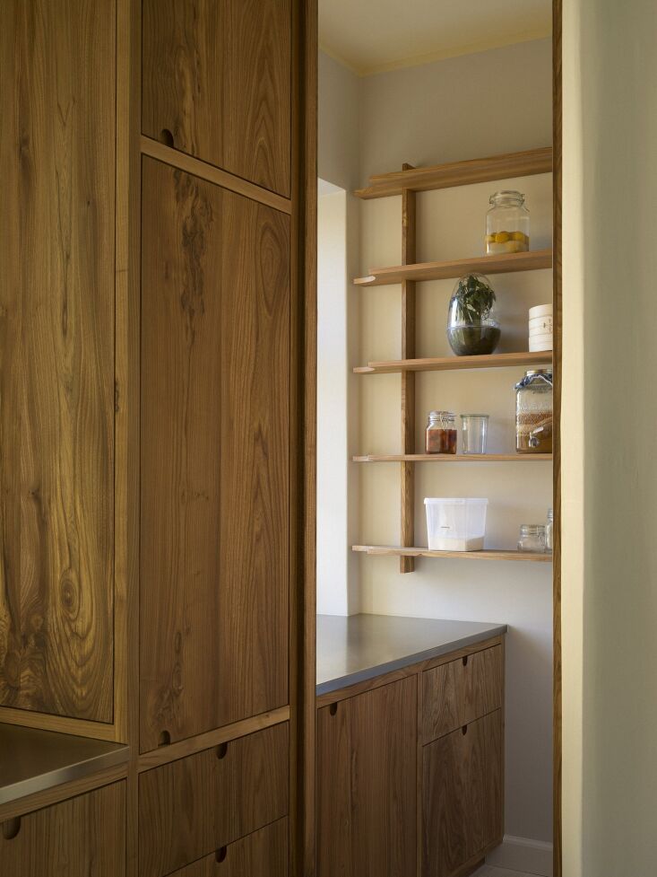 Wooden pantry shelves detached from a rustic brick wall to show textural contrast.