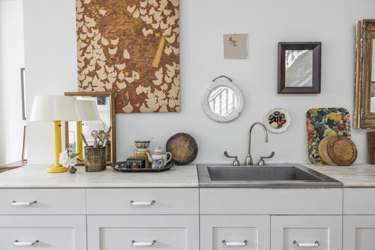 A minimalist 'stealth' kitchen in Harlem with no upper cabinets, decorated instead with mirrors and art.