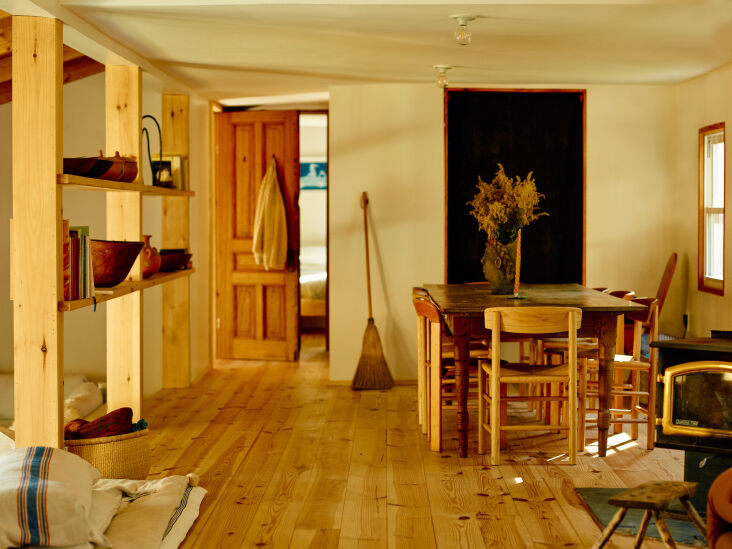 Dining area with an open shelf displaying wicker baskets and handmade ceramics.