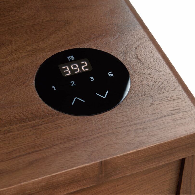 Detail shot of the digital touch control panel integrated into the wooden surface of the desk.