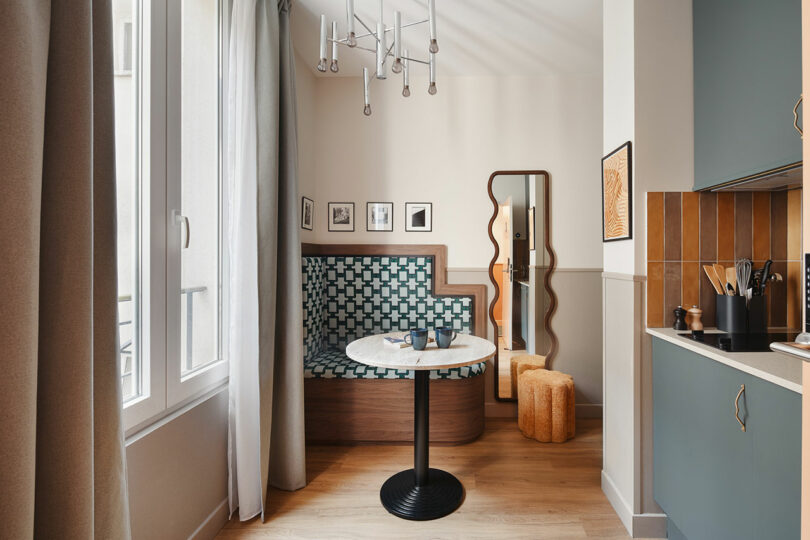 A modern dining nook featuring a patterned banquette, marble table, and blue kitchen cabinetry.