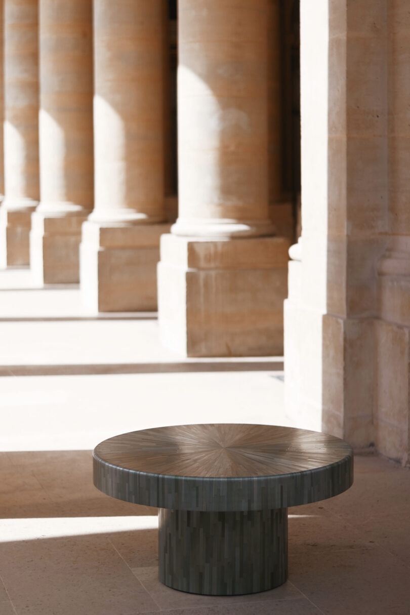 The Seahorse Table positioned on a stone walkway framed by grand classical columns in natural sunlight.