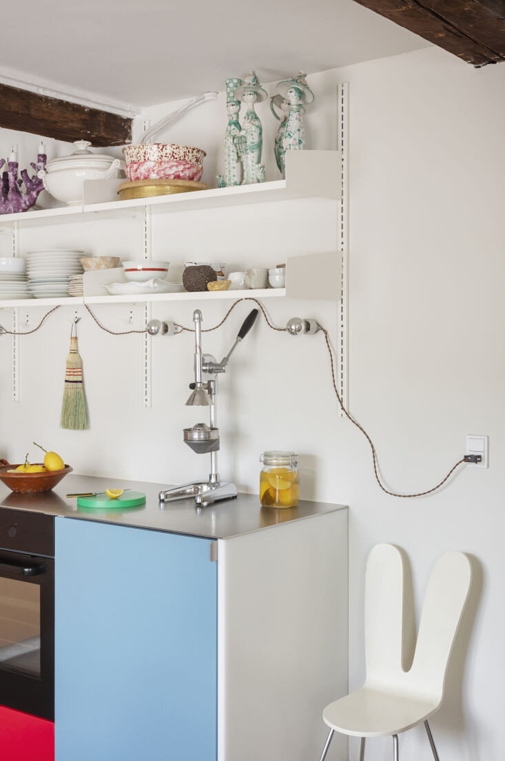 A modern kitchen in Copenhagen featuring white wall sconces fitted with silver-tipped light bulbs.