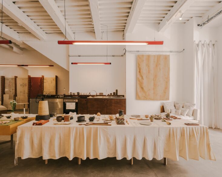 Long dining tables with embroidered linens inside a studio with polished concrete floors.