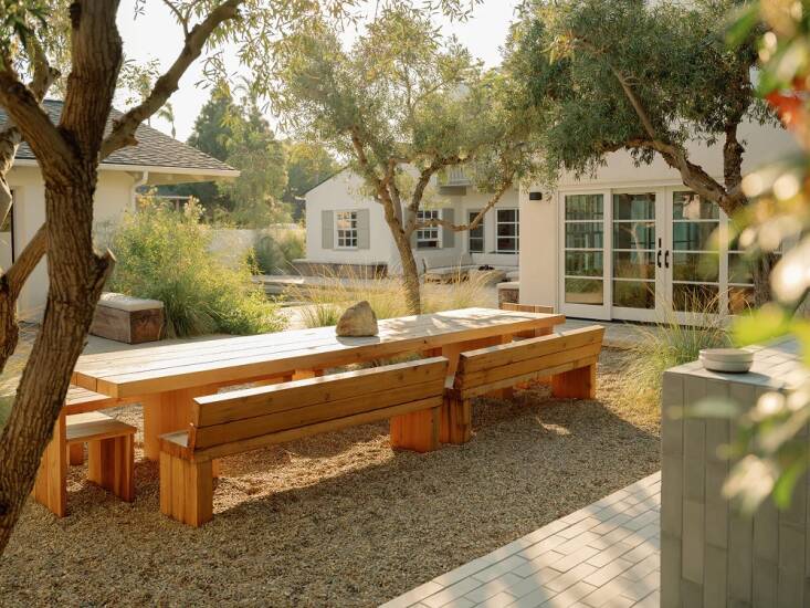 A stylish outdoor dining and work space by ORCA featuring modern furniture and lush greenery.