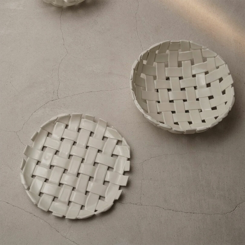 Two white ceramic platters with a unique hand-woven plait pattern on a textured surface.